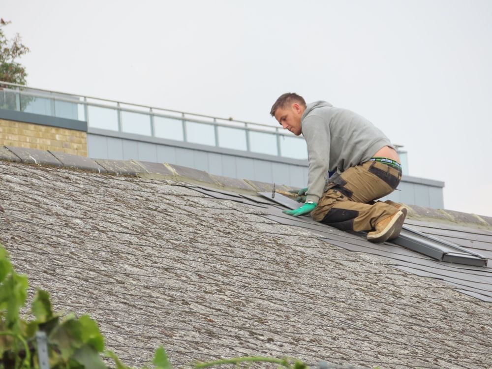 Roofer repairing shingles on a residential roof